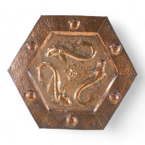 5 - An early 20th century copper wall plaque - hexagonal repousse decorated with three fish, 34cm wide.