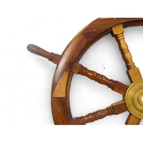 103 - A wooden ship's wheel - with eight turned spokes and brass centrepiece, diameter 90cm.