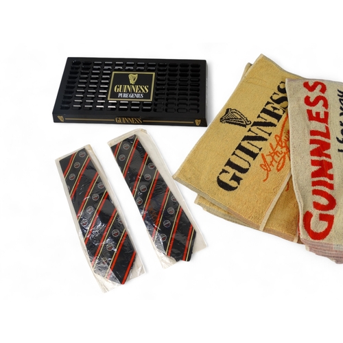 114 - A quantity of Guinness merchandising - including three t-shirts, a drip tray, two ties and bar towel... 