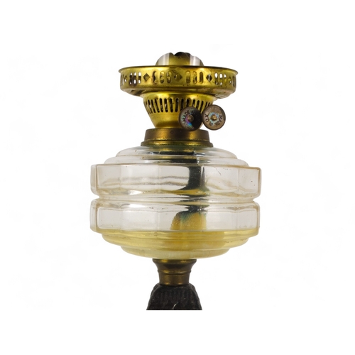 125 - A late 19th century oil lamp - with faceted clear glass reservoir, on a square tapering cast iron ba... 