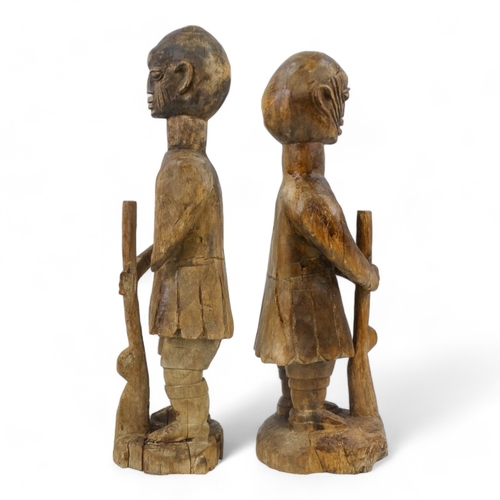 140 - Two carved wooden African figures - modelled as soldiers holding rifles, largest height 93cm.