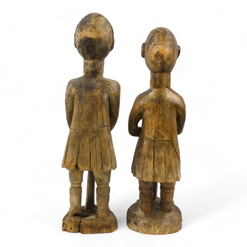 140 - Two carved wooden African figures - modelled as soldiers holding rifles, largest height 93cm.