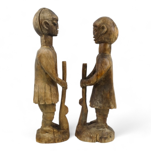 140 - Two carved wooden African figures - modelled as soldiers holding rifles, largest height 93cm.