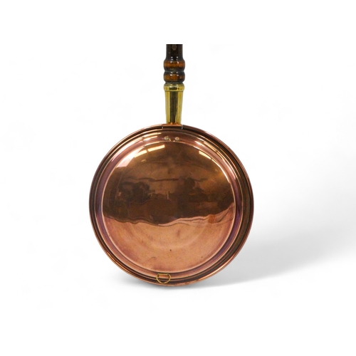 33 - A late 19th century copper warming pan - of typical circular form, with a turned wooden handle, 102c... 