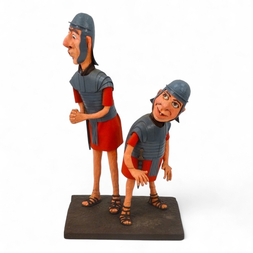 38 - A comical papier mache Roman figure group - modelled as two quizzical centurions, 85cm high.