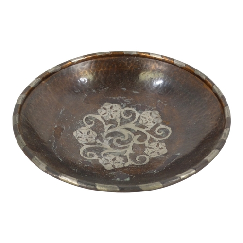 49 - Hugh Wallis (British, 1871-1943) a copper shallow bowl with pewter decoration - raised on three butt... 