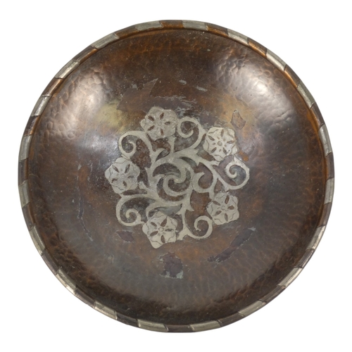 49 - Hugh Wallis (British, 1871-1943) a copper shallow bowl with pewter decoration - raised on three butt... 