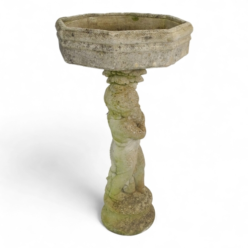 80 - A reconstituted stone bird bath modelled as a boy holding a fish - raised on a two tier plinth and w... 