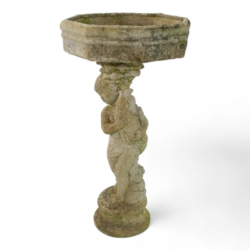 80 - A reconstituted stone bird bath modelled as a boy holding a fish - raised on a two tier plinth and w... 