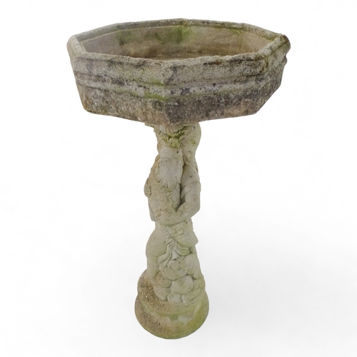 80 - A reconstituted stone bird bath modelled as a boy holding a fish - raised on a two tier plinth and w... 