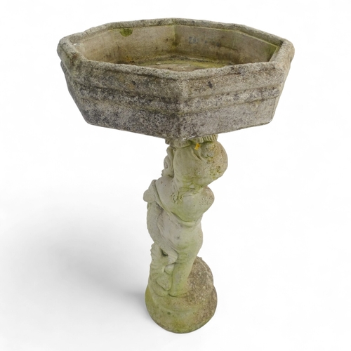 80 - A reconstituted stone bird bath modelled as a boy holding a fish - raised on a two tier plinth and w... 