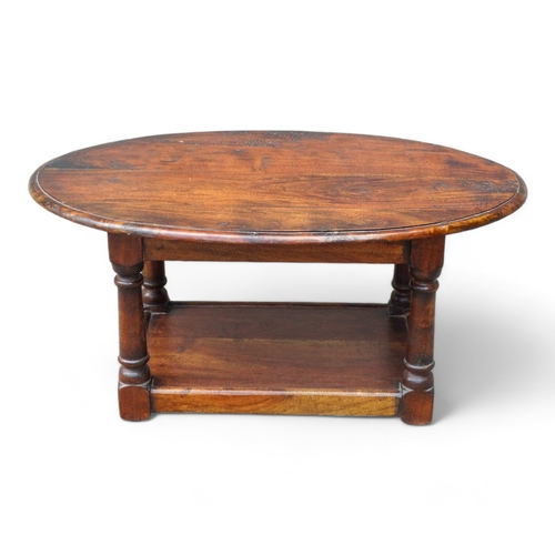 949 - A 20th century hardwood low table - the oval moulded top on square turned legs joined by an undertie... 