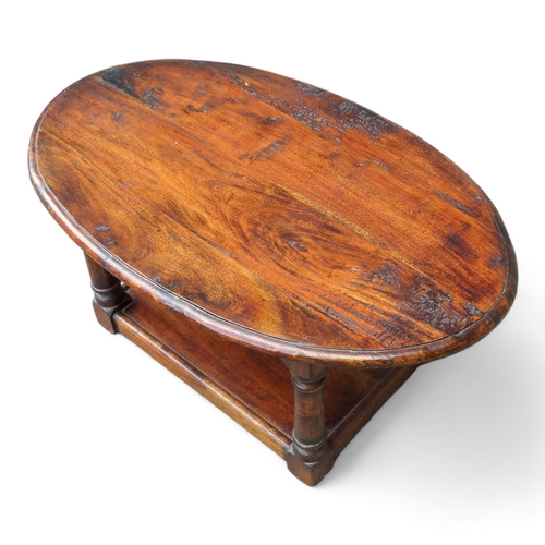 949 - A 20th century hardwood low table - the oval moulded top on square turned legs joined by an undertie... 