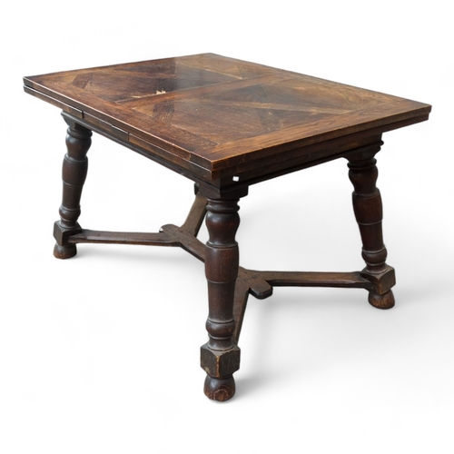 950 - A Spanish style oak draw-leaf table - the rectangular top with geometric veneers, on splayed square ... 