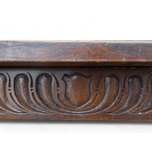 951 - A 17th century style oak refectory table - the cleated plank top above a carved frieze and square an... 