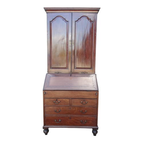 956 - A George III mahogany bureau bookcase - the upper section with shaped panel doors enclosing adjustab... 