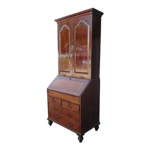 956 - A George III mahogany bureau bookcase - the upper section with shaped panel doors enclosing adjustab... 