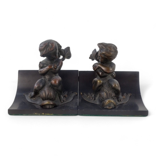 11 - A pair of bronze and slate book-ends - modelled as cherubs riding dolphins mounted on black slate, 1... 