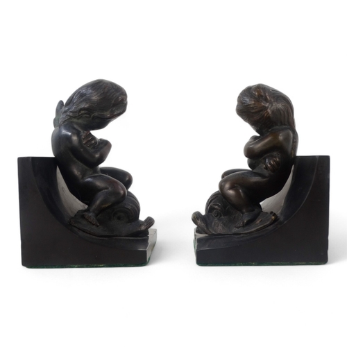 11 - A pair of bronze and slate book-ends - modelled as cherubs riding dolphins mounted on black slate, 1... 