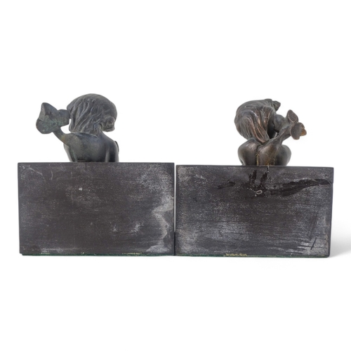 11 - A pair of bronze and slate book-ends - modelled as cherubs riding dolphins mounted on black slate, 1... 