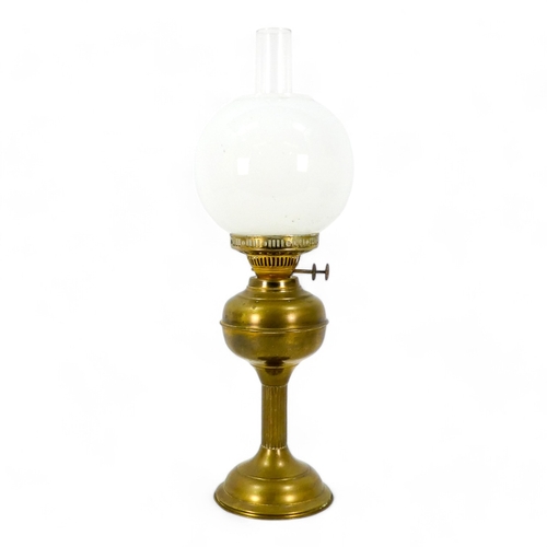 120 - An early 20th century brass oil lamp - with a milk glass globe shade, with a fluted column, 57cm hig... 