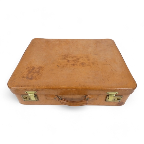 134 - A mid 20th century set of tan leather luggage - two large and one smaller, with brass catches and ta... 