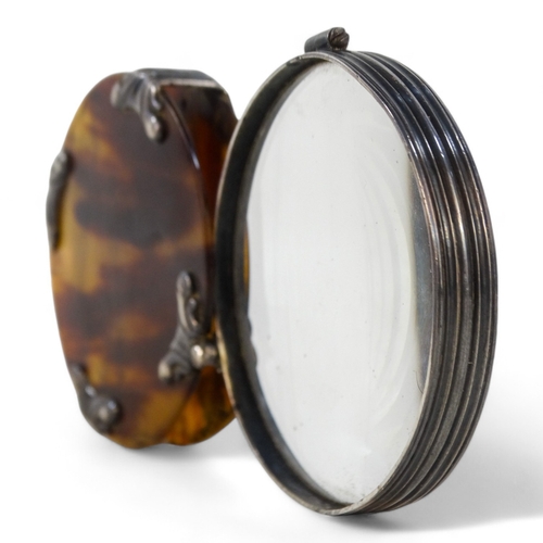 20 - A late 19th century white metal and tortoiseshell magnifier - circular with foliate mounts and a hin... 