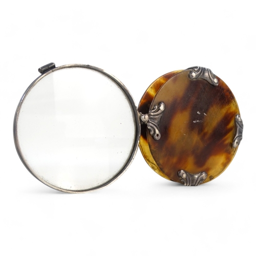 20 - A late 19th century white metal and tortoiseshell magnifier - circular with foliate mounts and a hin... 