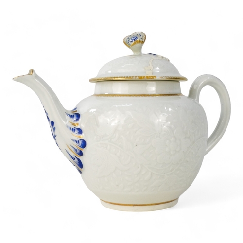 202 - A late 18th century bullet shaped teapot - with moulded floral and foliate decoration with blue and ... 