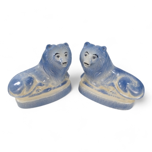 224 - A pair of Rye Pottery lions - recumbent, with a blue sponged finish, 18cm wide. (2)