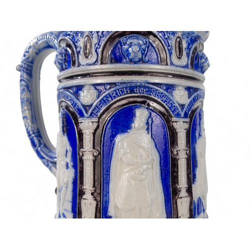 226 - An early 20th century German salt glazed tankard - blue and grey decorated with images of German cro... 