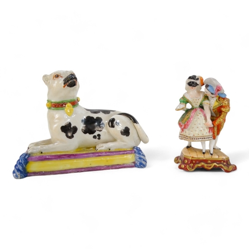 245 - A 19th century German porcelain dog - recumbent on a yellow cushion, 8cm wide, together with a pin c... 