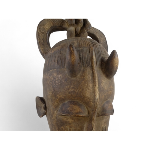 30 - A late 19th century African hardwood mask - polychrome painted, the bearded horned figure with a sma... 