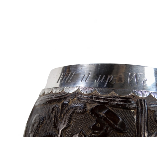 54 - An 18th century silver mounted coconut cup - the bowl carved with hunting figures and a musician, th... 