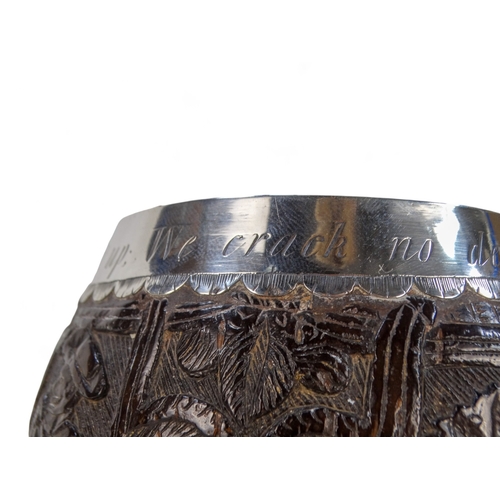 54 - An 18th century silver mounted coconut cup - the bowl carved with hunting figures and a musician, th... 