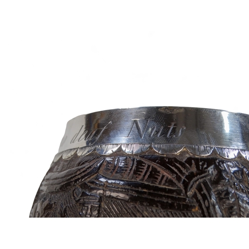 54 - An 18th century silver mounted coconut cup - the bowl carved with hunting figures and a musician, th... 