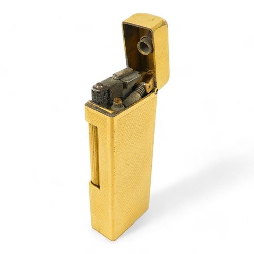 69 - A Dunhill gold plated cigarette lighter - of rectangular form and decorated with engine turning, tog... 