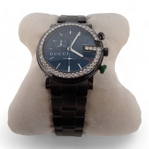 712 - A Gucci chronograph wristwatch - the black steel case with diamond G bezel, boxed with papers.