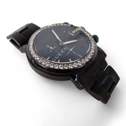 712 - A Gucci chronograph wristwatch - the black steel case with diamond G bezel, boxed with papers.