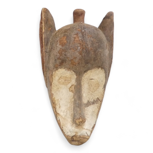 116 - A polychrome painted tribal African mask - with white eye sockets, pointed ears and a top knot, 39cm... 