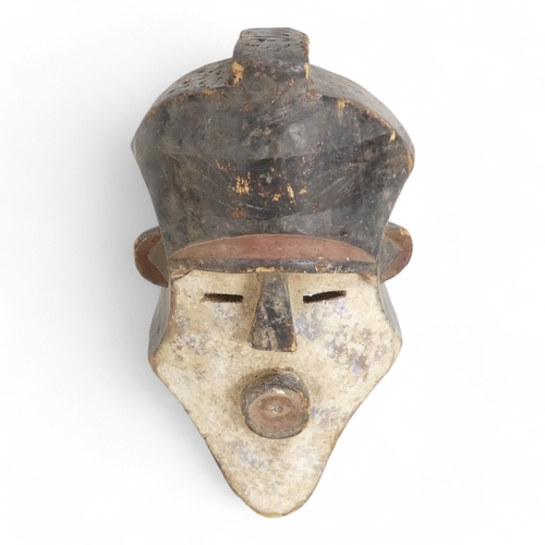 121 - A polychrome painted African mask - the head-dress with an ochre band, the white face with a pouting... 