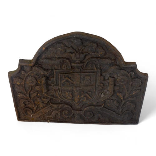 135 - An 18th century cast iron fire back - rectangular with an arched top and cast with armorial amongst ... 