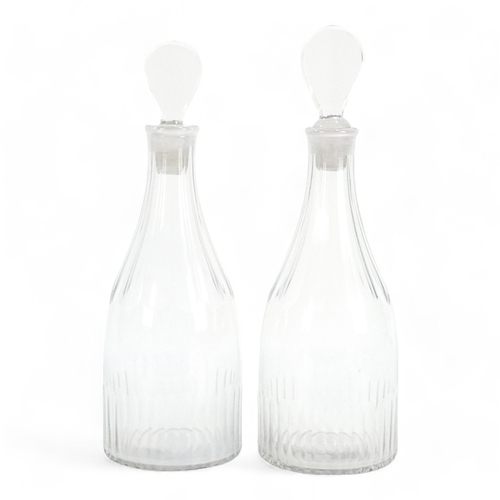 231 - A pair of early 19th century clear glass decanters - with fluted decoration and pear shaped stoppers... 