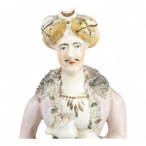 279 - A 19th century Staffordshire figure of a Turk - wearing a long pink jacket, 21cm high.