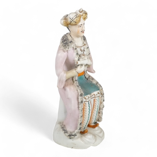 279 - A 19th century Staffordshire figure of a Turk - wearing a long pink jacket, 21cm high.