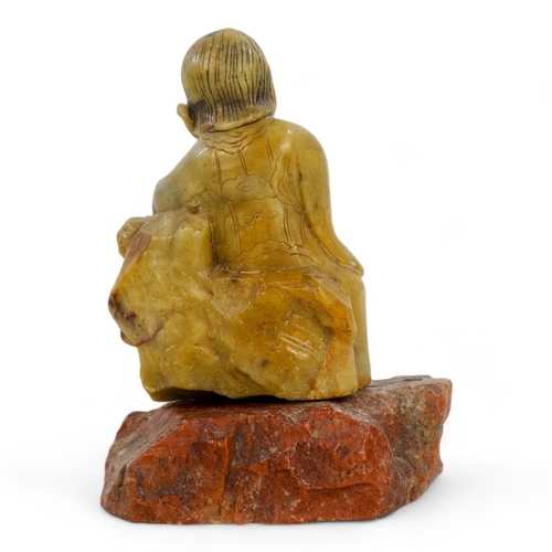 314A - An 20th century carved hardstone figure of Guangin - seated with a flower on a rocky base, 13cm high... 