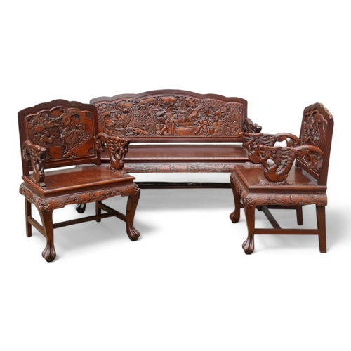 318 - A late 20th century Chinese carved hardwood two seat sofa - the back carved with figures in an exoti... 