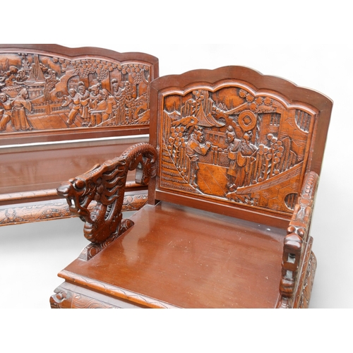 318 - A late 20th century Chinese carved hardwood two seat sofa - the back carved with figures in an exoti... 