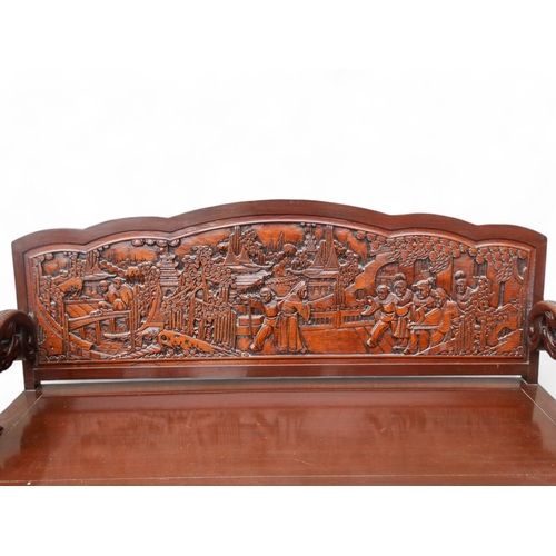 318 - A late 20th century Chinese carved hardwood two seat sofa - the back carved with figures in an exoti... 