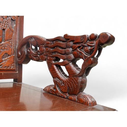 318 - A late 20th century Chinese carved hardwood two seat sofa - the back carved with figures in an exoti... 